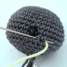Needle bringing the blush yarn out through the neck opening of the head