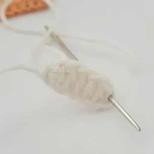 Orange crochet bow tie piece with a white chain and needle