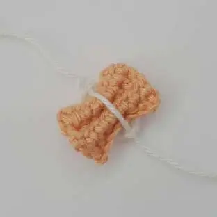 Orange crochet bow tie pinched inside a white loop