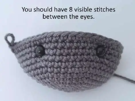 Crochet bat head with the safety eyes in place, 8 visible stitches between them