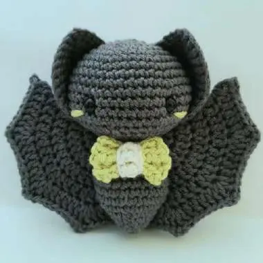 Finished gray crochet baby bat with a lime bow tie and wings spread