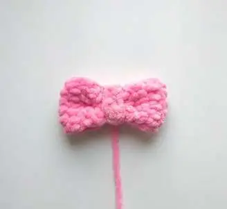 Finished pink crochet bow with the band wrapped around the middle