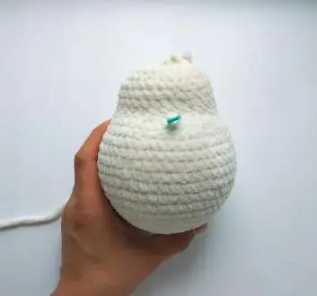 Crochet bunny body and neck with a green stitch marker on the belly